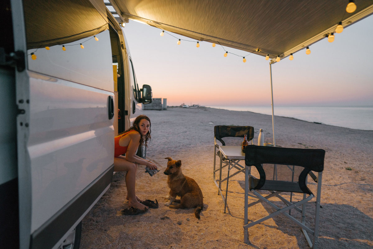 Young woman relaxing outside motorhome at the beach.